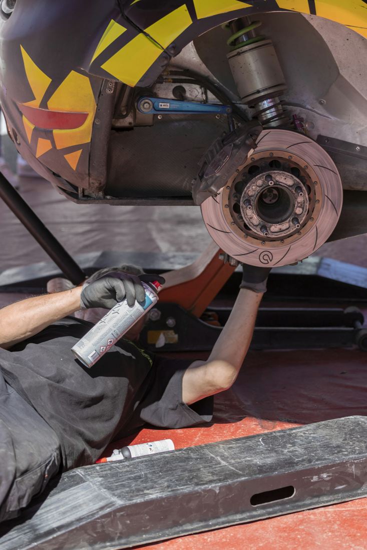 Mechanic cleaning a brake rotor on a lifted car